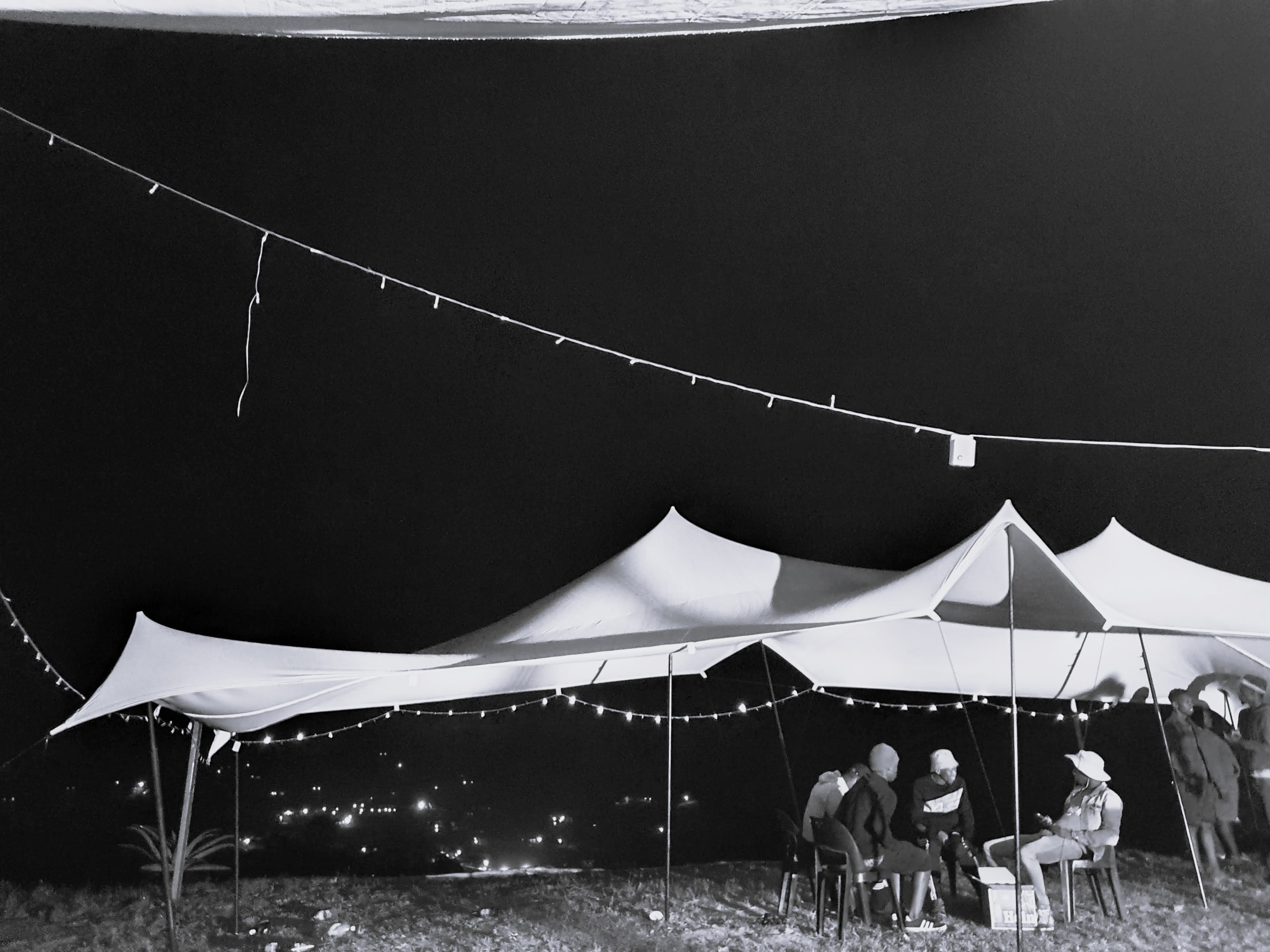 People sitting inside the Ventures Crew stretch tents at night in 2020